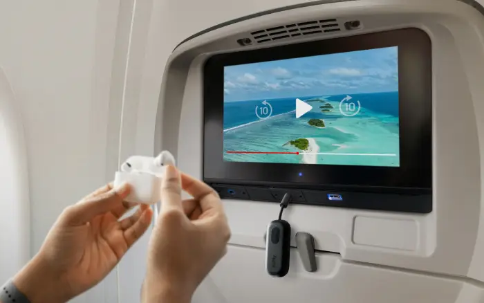 An Airfly adapter plugged into a seatback screen on an airplane.