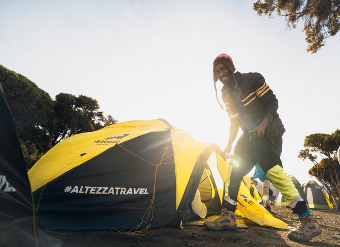 A mountain climbing guide smiles near travel tour operator tents. 