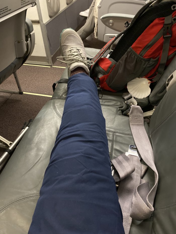 A woman's leg in an inflatable cast rests on a plane seat.