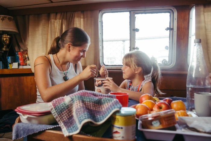 A woman and her young daughter smile as they eat ice cream inside of a motor home.