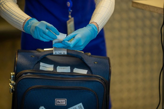 A ticket agent checks in luggage at an airport.