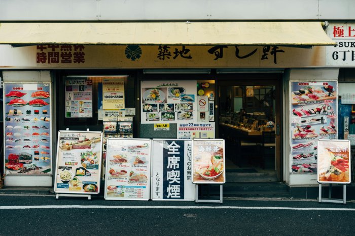 An Asian restaurant and its signage and large menus displayed outside.