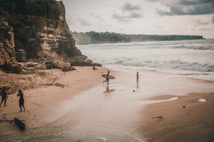 A young surfer runs to the water carrying his board to catch the waves in Bali.