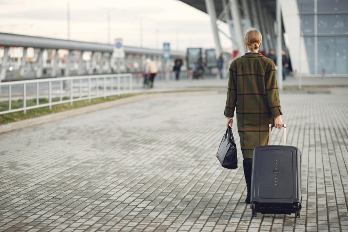 A business woman rolls a suitcase with her on the way to a train.