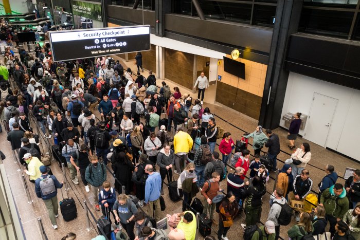 A long line of travelers waits to move through an airport security checkpoint