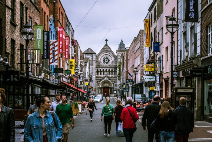 A crowded street in Dublin lined by busy storefronts.