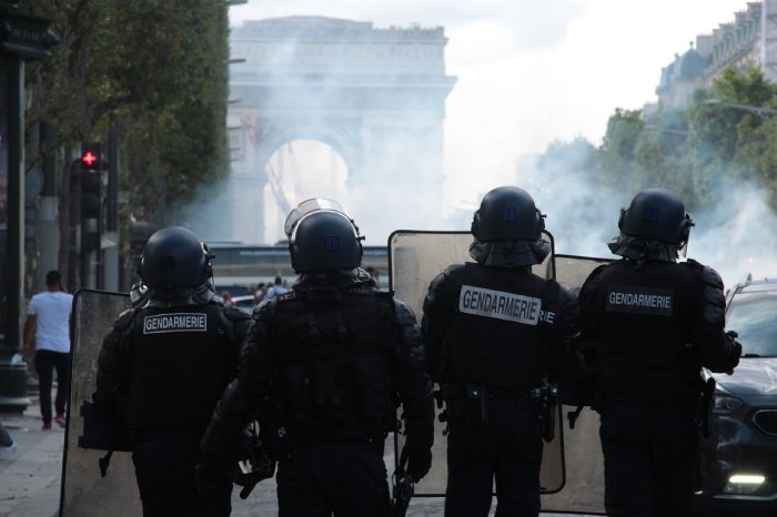 Four French policemen try to keep order on Les Champs Elysees with smoke in the air.