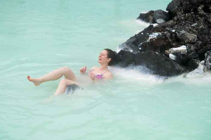 A woman smiles in the aquamarine waters of the geothermal Blue Lagoon Spa in Iceland.