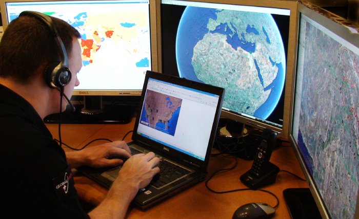 An operations center employee talking with someone on his headset while on multiple computers.