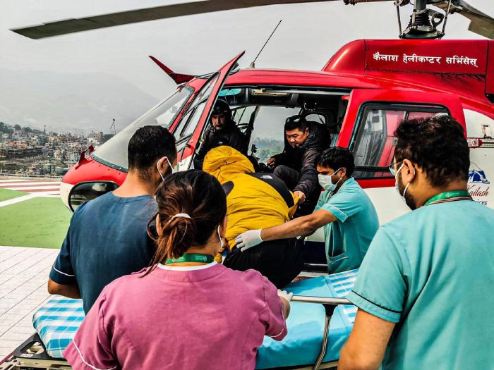 A mountain climber rescued via helicopter lands at a hospital with medical staff attending.