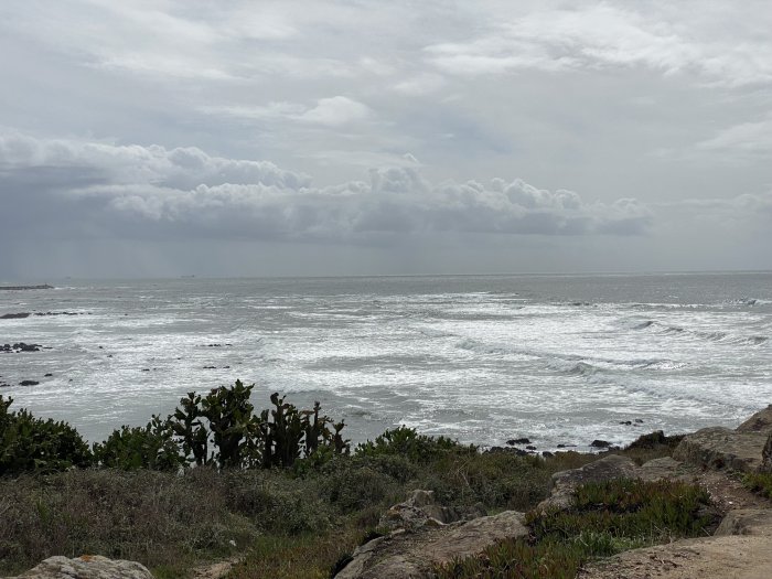 A Portuguese seaside, with ocean, rocky coast, and mostly cloudy skies.