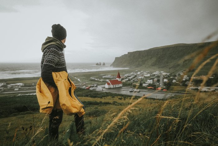 A Man in Warm Clothing Walking in the Countryside in Iceland near the ocean.