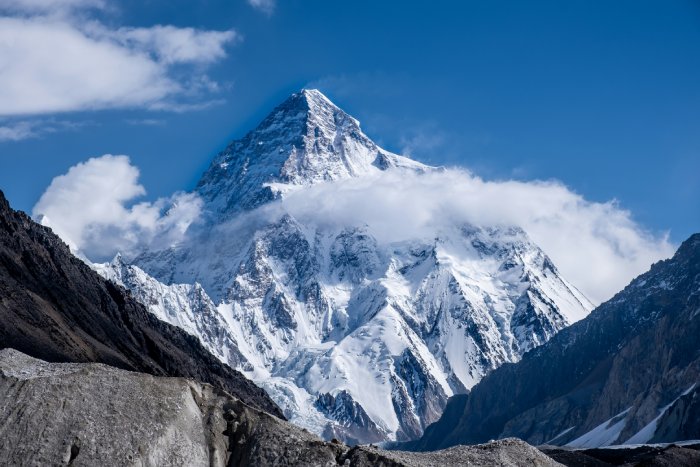 K2 stands tall and snowy among other mountains near it.