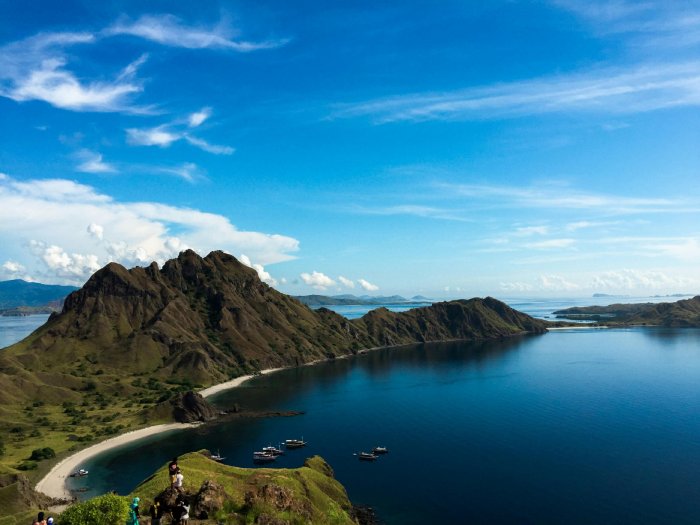 A beautiful lush, green mountain rises above the turquoise blue waters in Indonesia.