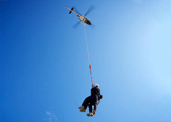 two people hanging froma helicopter's longline
