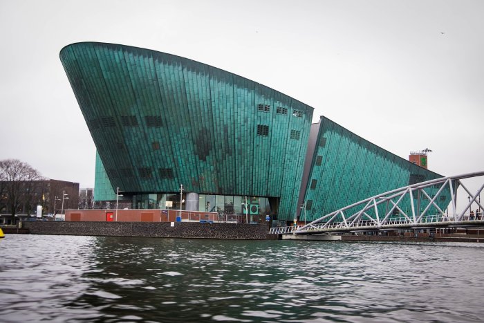 The NEMO Museum in Amsterdam stands high above the canal water on a cloudy day.