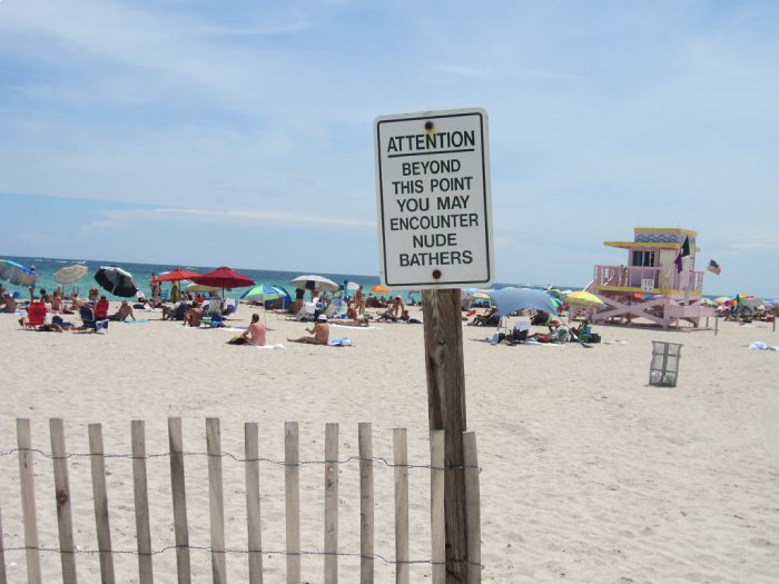A sign notifying people of nude sunbathers at a beach.