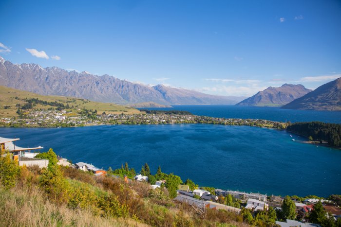 The water, hills, and mountains near Queenstown, New Zealand, on a sunny day.