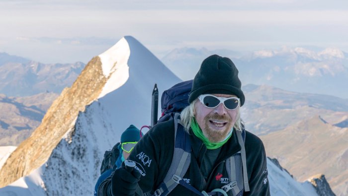 Sir Richard Branson climbs a snowy mountain at high altitude.