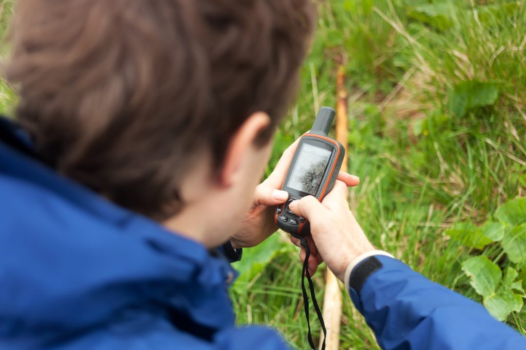 A man uses a satellite phone above grass.