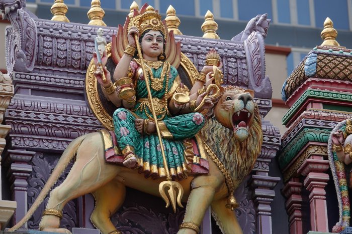 A sculpture of a goddess and a lion and temples in Singapore.