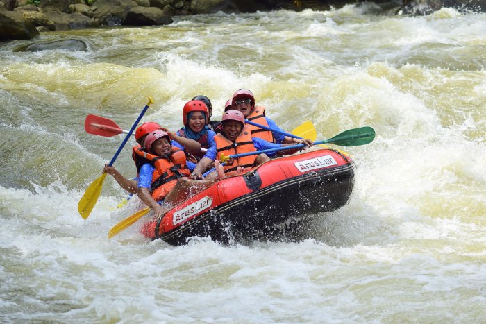 A group of smiling rafters making their way through some whitewater rapids.