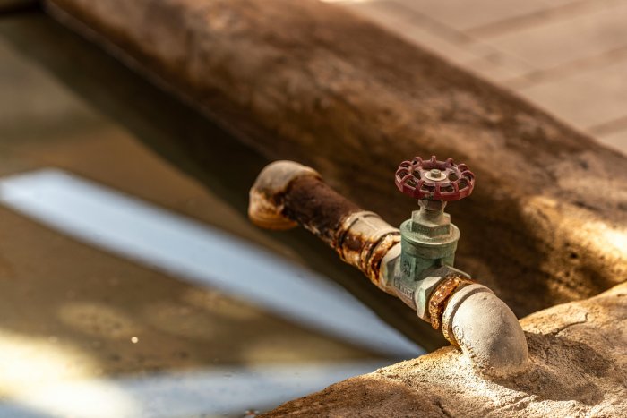 A rusty spigot for drinking water above a basin.