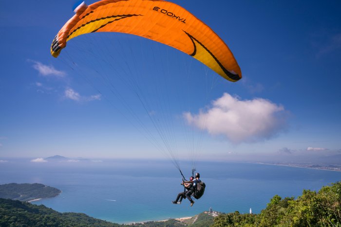 A tandem paraglide flight above a tropical area on a sunny day. 