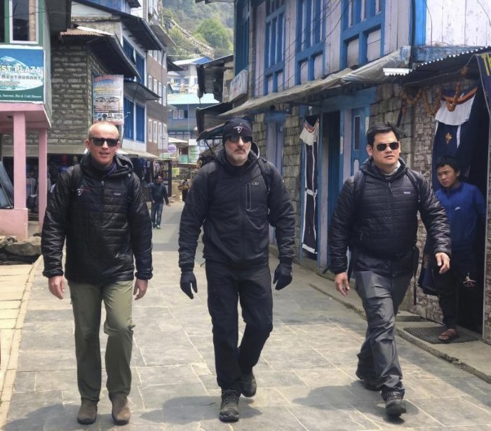 Three medical special operations men walk through a narrow street in a mountain village.