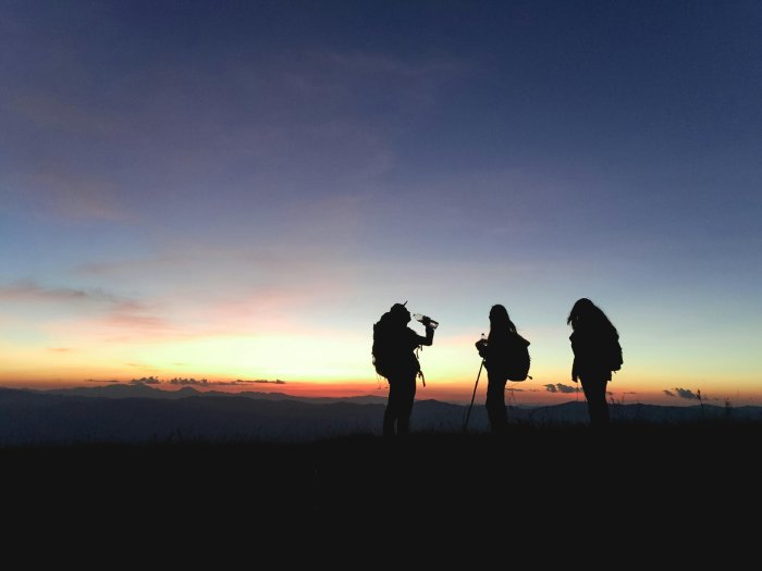 Three trekkers take a break at dusk.