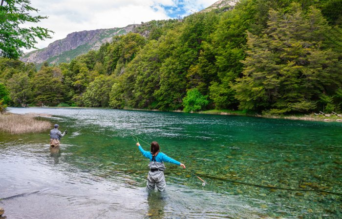 A man and woman flyfishing in a river.