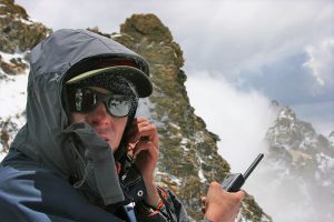 A Global Rescue operations team member uses a satellite phone to make a call at elevation in the high mountains.