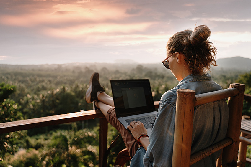 A woman works remotely from her computer while traveling.