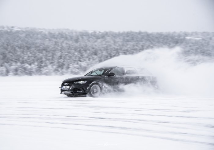 An Audi drifts through a field of snow.