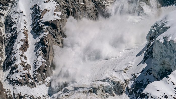 An avalanche careens down a snowy mountain side.