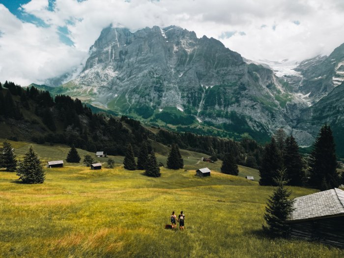 A couple stands in a field high up in the Swiss Alps.